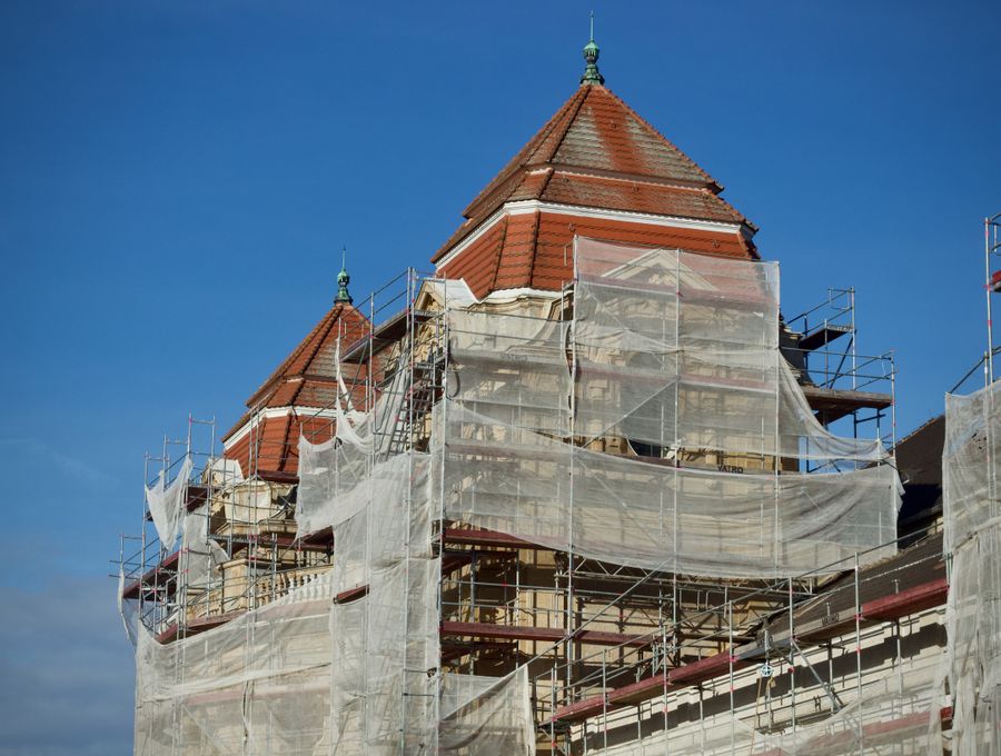 A tower roof with sheeted scaffolding around it, against a blue sky